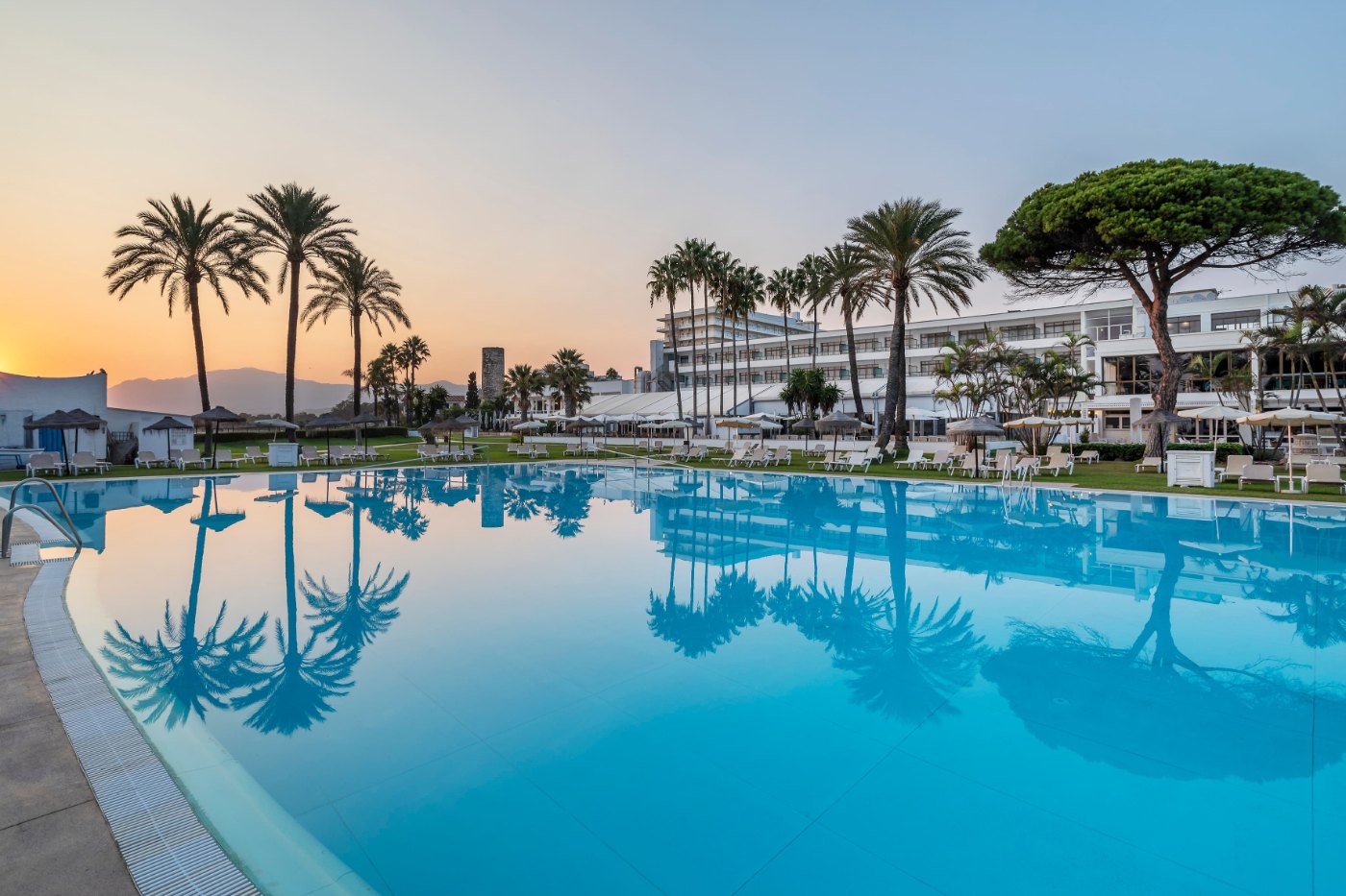 Outdoor pool with the hotel building at sunset