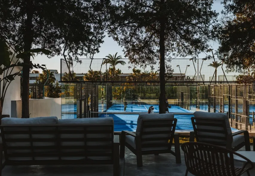 Club terrace looking onto glass padel courts at sunset